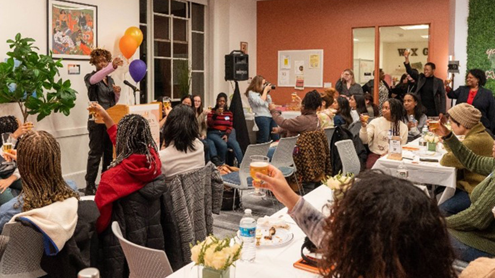 Roomful of event attendees applauding a speaker at the podium